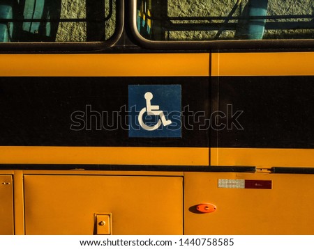 Exterior of a school bus that in the center of the image shows the symbol of accessibility, that the bus can take people from wheelchair. Royalty-Free Stock Photo #1440758585