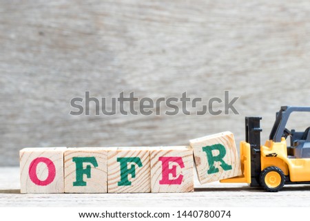 Toy forklift hold letter block R to complete word offer on wood background