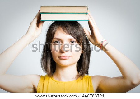 beautiful young woman hold books on head isolated on background