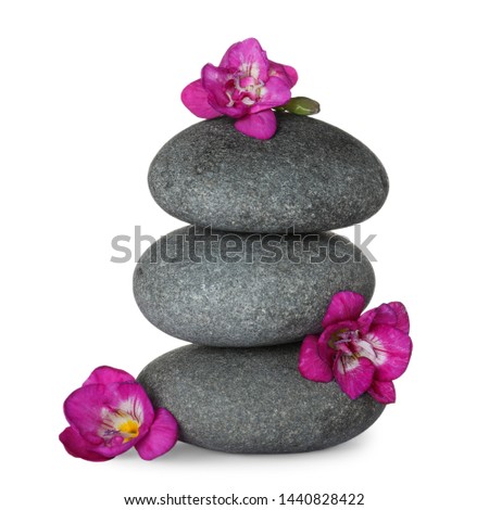 Stack of grey spa stones and fresh flowers isolated on white