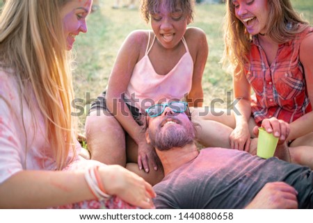Friends sitting on grass and having fun at summer holi festival