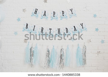 
inscription happy birthday, boy's birthday decor, foil decorations, garland on a white brick wall