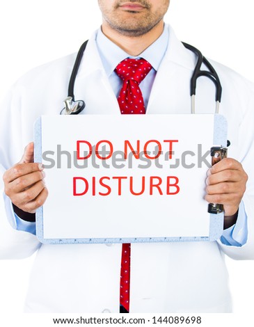 Closeup portrait of serious health care professional with red tie and stethoscope, holding a sign which says "do not disturb", isolated on white background