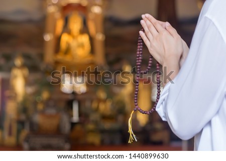 Religious Asian buddhist woman praying, chanting mantra to the lord Buddha with buddhist style rosary beads in hand Royalty-Free Stock Photo #1440899630