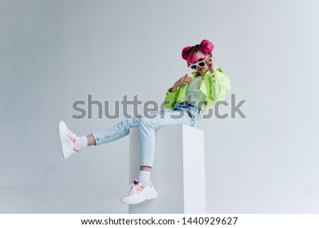 woman with pink hair sits on a cube in the studio
