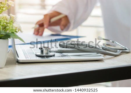 Doctor working in hospital writing prescription clipboard, working an Laptop on desk in hospital with report analysis, Healthcare costs and fees in medical hostpital office