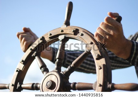 Steering hand wheel ship on sky background, hand hold hand wheel