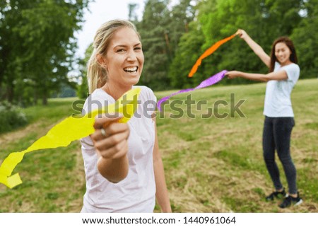 Young women play with colorful ribbons in a meadow at a teambuilding event