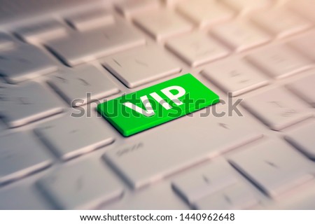 Close-up view on gray conceptual keyboard - VIP green key. blurred in motion background.