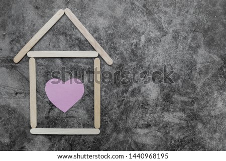 Home made from wooden ice-cream sticks with heart shape on black grunge wall