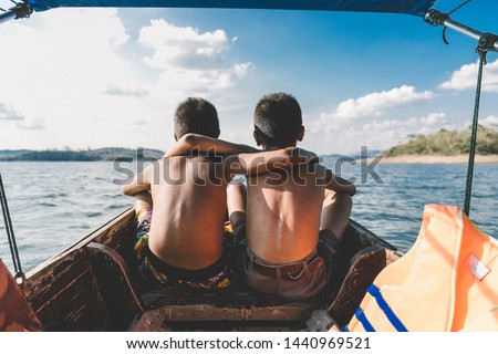 Two boy sit on the boat looking beautiful sky add noise picture. Dear friend