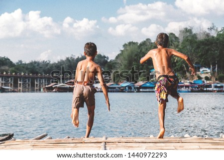 Two boys are jumping to river add noise picture.