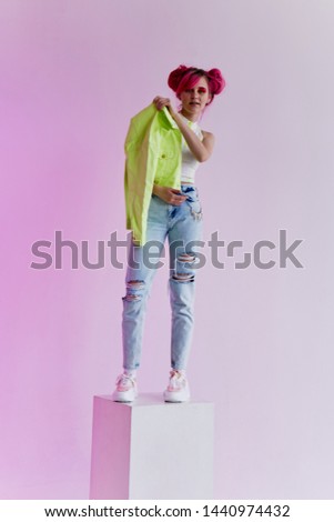 woman with pink hair stands on a cube