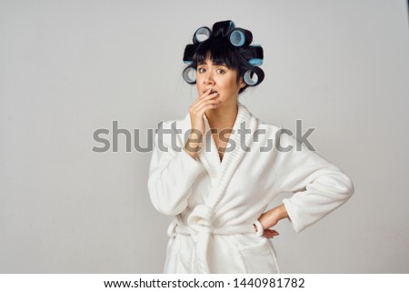 woman in white coat with hair curlers                               