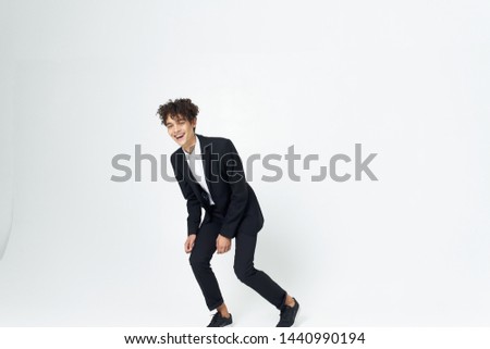 curly guy in a business suit runs around the bright room                      