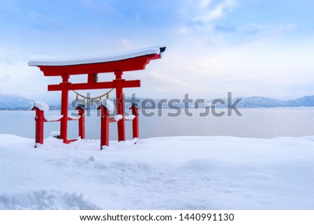 Torii gate of Goza no Ishi Shrine on snow, out over the Lake Tazawa and mountains background, Semboku, Akita Japan