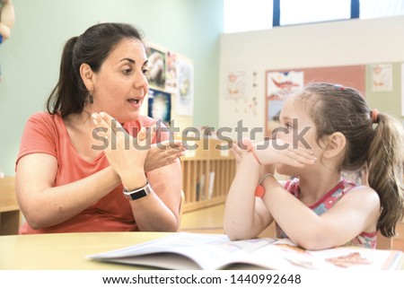 Sign language teacher in a extra tutoring class with a deaf child girl using American Sign Language.