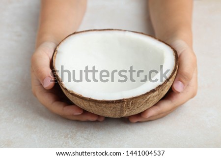 Half of natural exotic coconut in hands on neutral background.