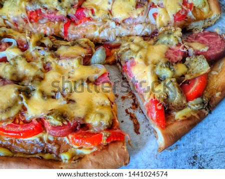 homemade pizza with tomatoes, meat and cheese on a baking sheet.