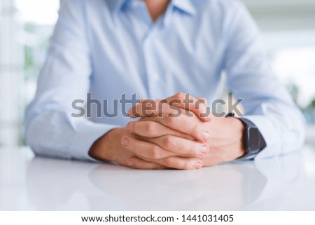 Close up of man crossed hands over white table
