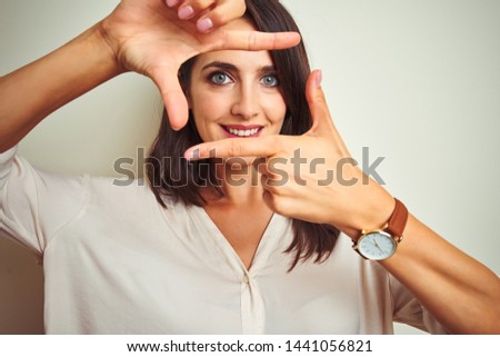 Young beautiful woman wearing casual shirt standing over white isolated background smiling making frame with hands and fingers with happy face. Creativity and photography concept.