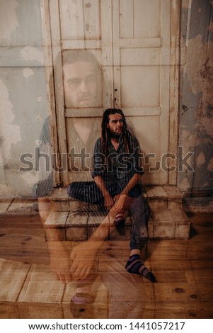Double exposure. Enlightened cute man with a dreadlocks on his head and a beard in art scene