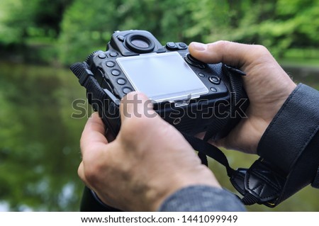 A photographer adjusts the camera. The fingers of the photographer are pushing the camera's buttons. Close-up
