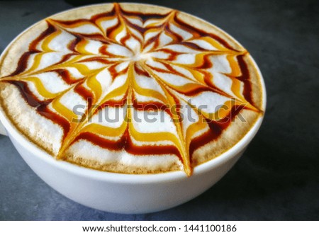 Coffee latte art  caramel and chocolate sauce   with white milk foam  on cement surface work desk