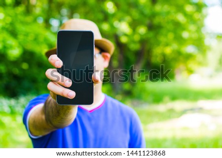 man holding a smartphone against nature