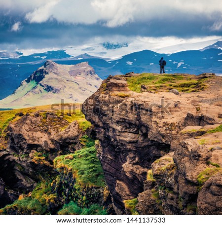 Photographer takes picture on the edge of cliff. Stunning summer view of Dyrholaey Nature reserve. Splendid morning scene of southern Iceland, Europe. Traveling concept background.
