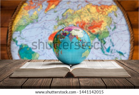 Ancient book and Earth globe with stars and universe art. Magic and space theme. Blue light on background. Planet concept. Place for text and infographic. Abstract history and astronomy theme.
