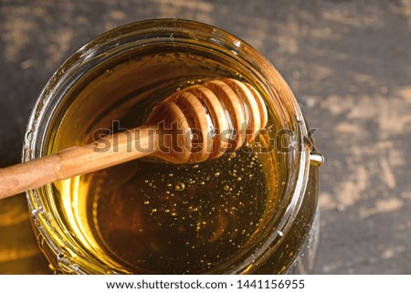 honey jar with honey and wooden stick