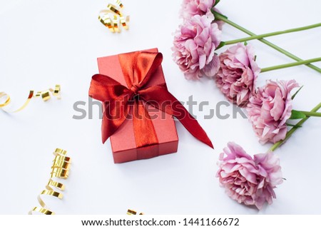 White background with red gift box and peony flowers, top view. Flat lay style