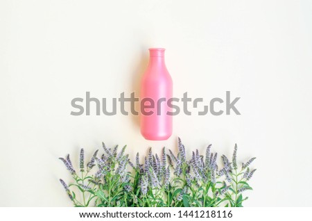 Coral-colored cosmetic bottle with a bouquet of blooming mint.