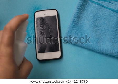 cleaning smart phone screen on color blue background. mobile phone cleaning. 
