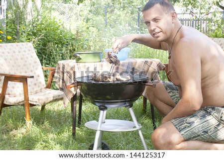 Adult man preparing a barbecue in the summer garden