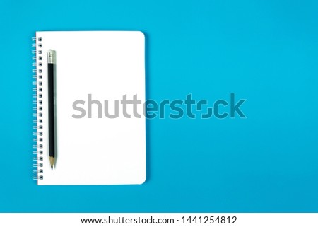 Flat lay. Blue background image With an empty white book placed to allow for more text, numbers, pictures or symbols As needed.