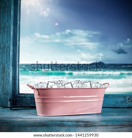 Summer window background and free space for your decoration. Metal container with cold ice and free space for your bottle. Landscape of ocean with waves and sun light. Dark blue sky. 