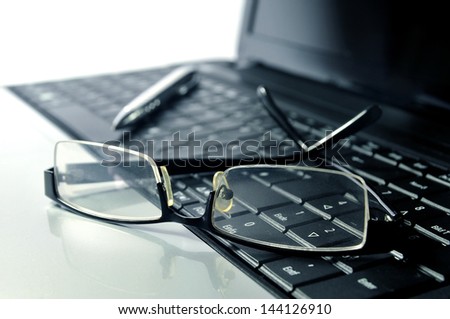 Business - Glasses and ball pen on top of a laptop