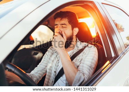 Tired man yawning while driving his car Royalty-Free Stock Photo #1441311029