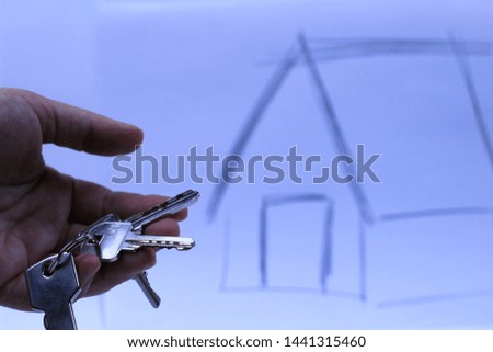 Hand holding bunch of keys and house in white background. Outdoors photography.