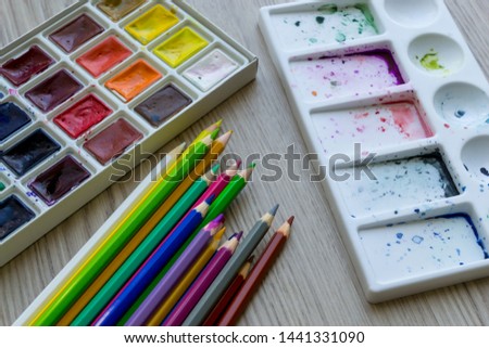 Creative artistic education concept - the box with the set of colorful watercolor paint and the set of drawing pencils close up