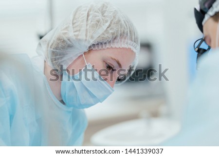 Surgeons perform the operation. Portrait of a surgeon girl leaning over a patient