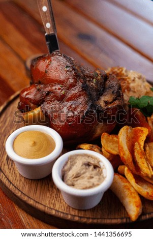 Fat pork knuckle with baked crispy potatoes and classic german braised cabbage on a wooden table