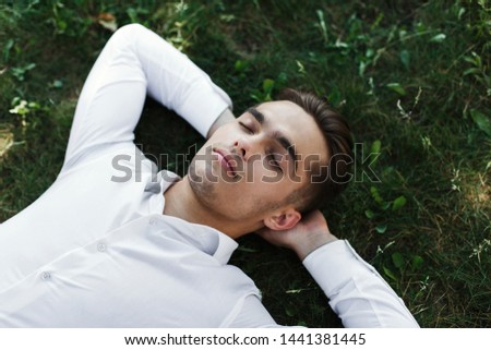Handsome young man in a white shirt lies on the ground