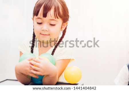 Beautiful baby kids girl kindergarten playing colorful ball at interior room home