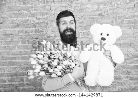 Wow. Love date. international holiday. Spring gift. Bearded man hipster with flowers. Bearded man with tulip bouquet and bear. Flower for March 8. Womens day. Natural beauty. Capturing a happy moment.