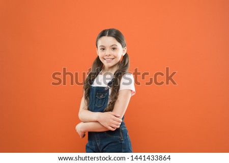 Being great every day. Fashion baby girl. Cute little fashion model on orange background. Small child with fashion look. Adorable kid with long brunette hair in casual fashion style.