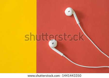 White in ear headphones photography on red color and left copy space flip side yellow background, minimal trendy concept.