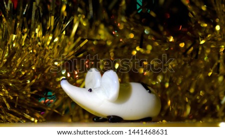 Christmas greeting from a rat or mouse. Happy Chinese New Year year of rat. The symbol of the New Year on the background of golden garland ornaments. Christmas Rat